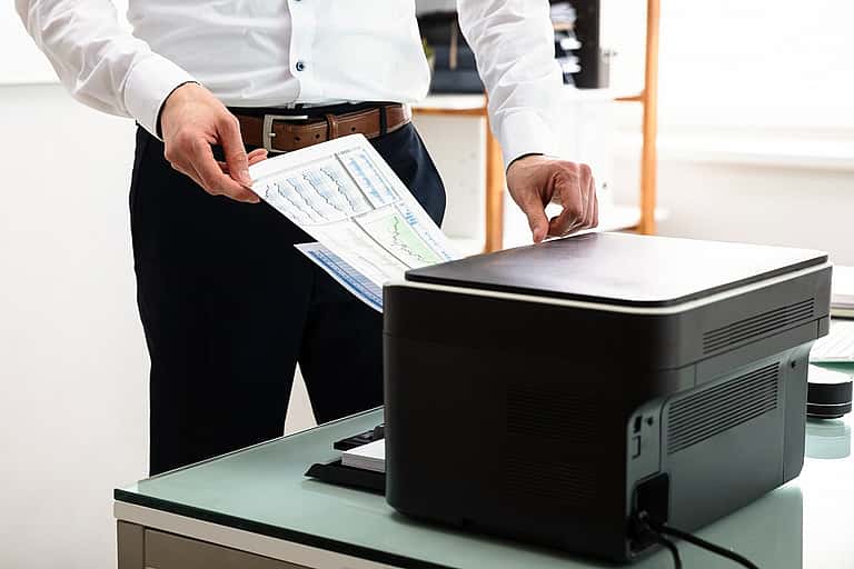 Close-up of hands operating a printer, emphasising grenke's leasing options for laser, LED, multifunction, and 3D printers, supporting resellers with flexible, expert-driven financing partnerships in the UK.