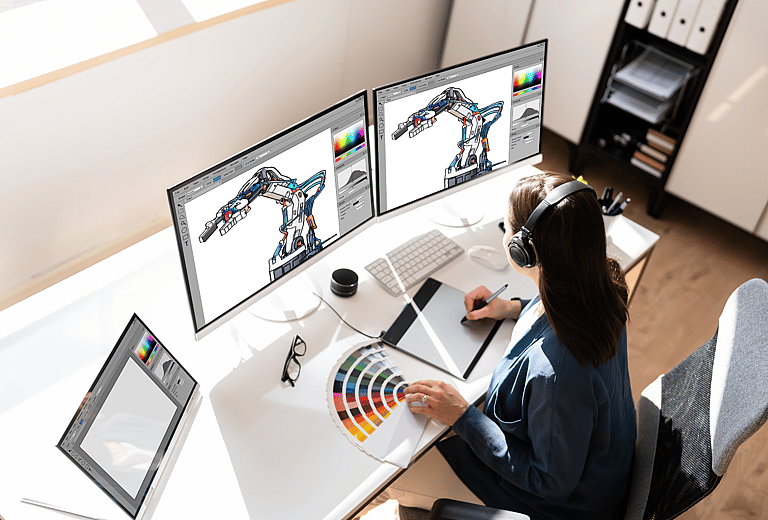 Close-up photo of a woman using professional graphic software on advanced IT hardware, including computers and screens. Illustrates how grenke’s IT financing solutions support businesses by bundling hardware and software into one agreement, enhancing hybrid working, and offering affordable technology leasing to out-tech competitors.